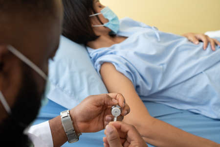 African American doctors wear medical masks and vaccinated to women patients for the prevention of   flu. Concept of immunization from inoculationの写真素材
