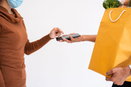 Asian delivery man holding holding a bag of fresh food for giving to customers and holding...