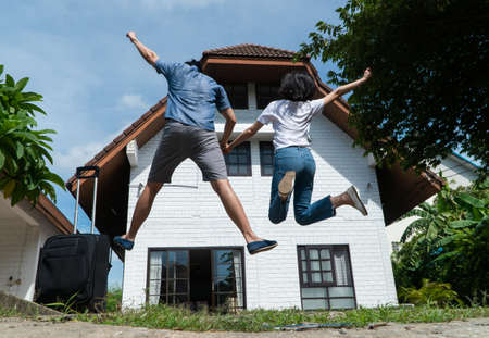 Happy couple in front of the New Home On Moving In Day, and start a new life family. Concept of homeowner and relocationの写真素材