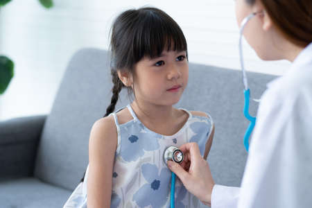 Asian woman pediatrician doctor hold stethoscope for exam a little girl patient and heck heart lungs of kid, Good family doctor visiting child at home, Healthcare and medicine for childhood concept.の写真素材