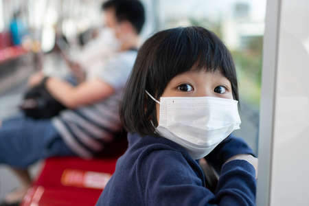 Little girl with surgical mask face protection flu and Virus outbreak in public transportation (skytrain or subway). Concept of New normal lifestyle, Using public transport to travel to school.の写真素材
