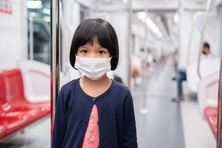 Little girl with surgical mask face protection flu and Virus outbreak in public transportation (skytrain or subway). Concept of New normal lifestyle, Using public transport to travel to school.の写真素材