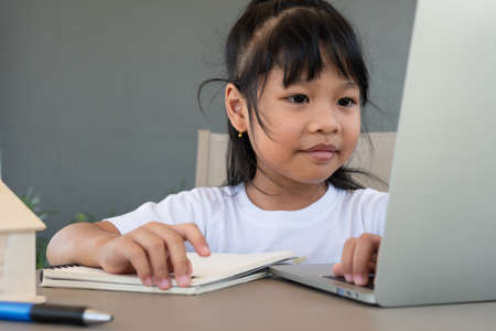Asian girl student using the laptop for online learning class and doing homework at home, Education and distance learning for children Homeschooling conceptの写真素材