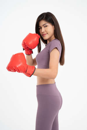 Portrait of beautiful Asian woman standing smile wearing the red boxing gloves,  studio shot isolated on white background, Concept of fitness, exercise and healthyの写真素材