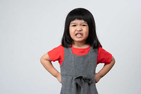 Portrait of Asian angry and sad little girl on white isolated background, The emotion of a child when tantrum and mad, expression grumpy emotion. Kid emotional control conceptの写真素材