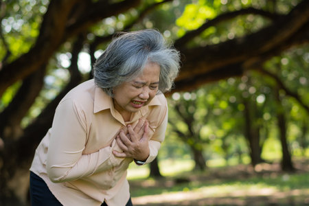 Senior Asian woman problem chest pains or heart attack outdoor in park, heart problems, a senior...