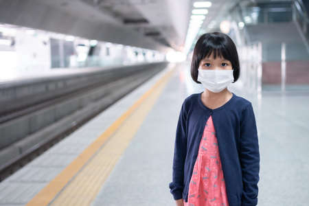 Little girl with surgical mask face protection flu and Virus outbreak in public transportation (skytrain or subway). Concept of New normal lifestyle, Using public transport to travel to school.の写真素材