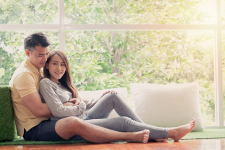 Happy couple sitting on the sofa and being a man teases his girlfriend with love in the living room...