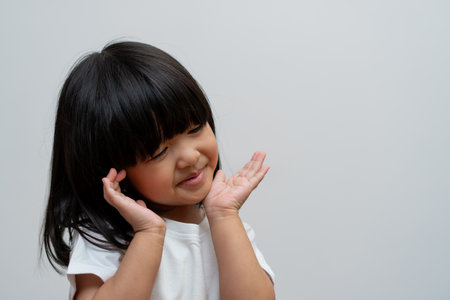 Portrait of happy and funny Asian child girl on white background, a child looking at camera. Preschool kid dreaming fill with energy feeling healthy and good conceptの写真素材