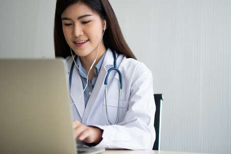 Asian woman doctor is online visiting with a patient on the internet application and Listening of the symptoms and explains how to treat the initial disease, Concept of Medical technology.の写真素材