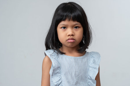 Portrait of Asian angry and sad little girl on white isolated background, The emotion of a child when tantrum and mad, expression grumpy emotion. Kid emotional control conceptの写真素材