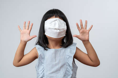 Portrait of funny Asian girl kid with protective face mask. Concept of kid going back to school and new normal lifestyleの写真素材