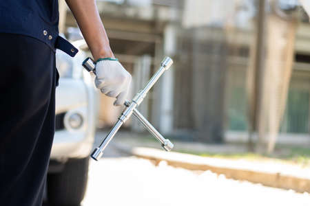 Focus car mechanic hand holding wrench for change the wheel on a broken car, uses tools or equipment, tries to solve problems by professional, Car Repairing and insurance conceptの写真素材