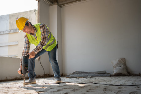 Construction worker Using an electric jackhammer to drill perforator equipment making holes before...