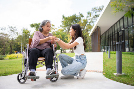 Asian careful caregiver or nurse hold the patient hand and encourage the patient in a wheelchair....
