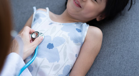 Asian woman pediatrician doctor hold stethoscope for exam a little girl patient and heck heart lungs of kid, Good family doctor visiting child at home, Healthcare and medicine for childhood concept.の写真素材