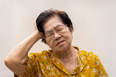 A senior woman who has a severe headache suffers from a stroke ,brain disease,patient holding head with her hand,suffering from senile dementia,memory disorders, confused old elderly with Alzheimerの写真素材