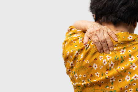 Sick senior woman with back neck and shoulders pain on the joint and muscle. Close-up of wrinkled hands rubbing their neck-collar area, osteoarthritis, neurological diseases. Medicine conceptの写真素材