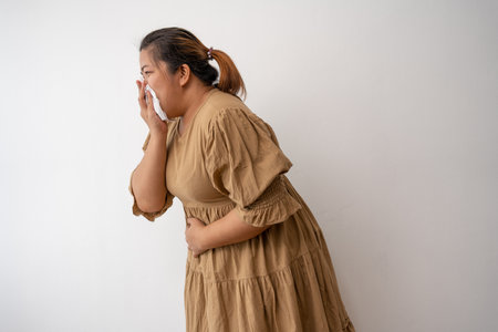 Young Asian plus size woman hand on stomach because nausea, painful disease feeling unwell,  may develop gallstones or Cholecystitis. From gastritis and enteritis to people and health care concepts.の写真素材