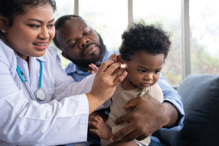 Pediatric doctor examining ear for a hearing test examining cute little girl in medical healthcare hospital or clinic. Smiling African American Baby whit pediatrician in hospitalの写真素材
