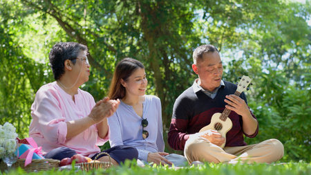 Happy old elderly couple spouses relaxing and sitting on a blanket in the park and sharing few...