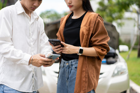 Two Drivers using a smartphone to exchange phone numbers and social media after a car accident. Concept of claim insurance for a car accident online after send photo and evidence to insurance companyの写真素材