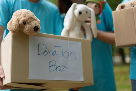 Happy young Asian students diverse volunteers hold donate box and toys for charity to share children...