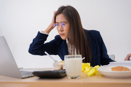 Busy and tired businesswoman eating spaghetti for lunch at the Desk office and working to deliver financial statements to a boss. Overworked and unhealthy for ready meals, burnout concept.の写真素材