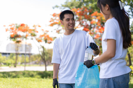 Happy young Asian students diverse volunteers with garbage bags cleaning area in the park, The concept of environmental conservation on world environment day, recycling, charity for sustainability.の写真素材