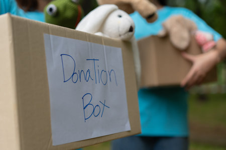 Happy young Asian students diverse volunteers hold donate box and toys for charity to share children...