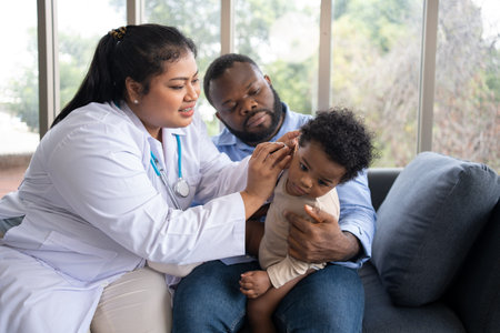 Pediatric doctor examining ear for a hearing test examining cute little girl in medical healthcare hospital or clinic. Smiling African American Baby whit pediatrician in hospitalの写真素材