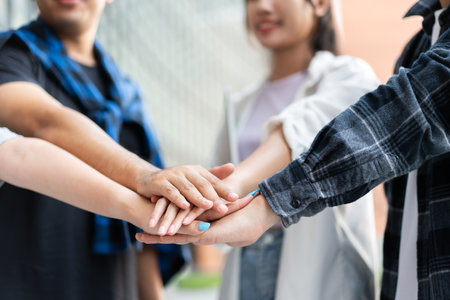 Group of cheerful young Asian entrepreneurs joining hands together to celebrate, excited success for achievements obtained. Undergraduate students celebrate success after end project, teamwork conceptの写真素材