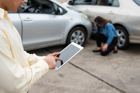 Businessman using a smartphone to take a photo to send to insurance. Concept of claim insurance for a car accident online after send photo and evidence to the insurance companyの写真素材