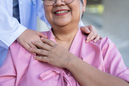 Asian careful caregiver or nurse hold the patient hand and encourage the patient in a wheelchair.  Concept of happy retirement with care from a caregiver and Savings and senior health insurance.の写真素材