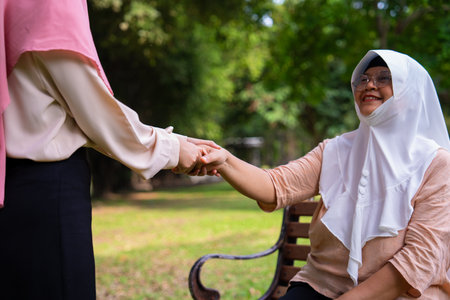 Muslim careful caregiver or nurse taking care of the patient in the hospital park. Happy Muslim mother in hijab hugging daughter. Concept of Savings and Senior Health Insurance, a Happy Familyの写真素材