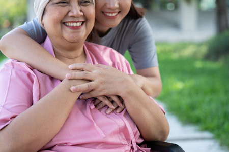 Asian careful caregiver or nurse and woman with cancer is sitting in a wheelchair. in the garden....