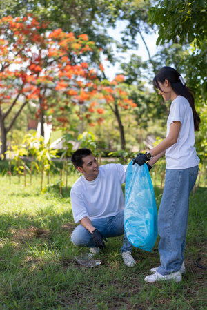 Happy young Asian students diverse volunteers with garbage bags cleaning area in the park, The concept of environmental conservation on world environment day, recycling, charity for sustainability.の写真素材