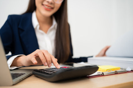 Portrait of smiling business asian woman at modern office desk using laptop to work and write notes, Business people employee freelance online marketing e-commerce telemarketing concept.の写真素材