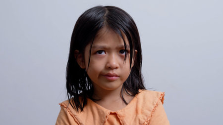 A little Asian girl sitting in a room corner and crying.の写真素材