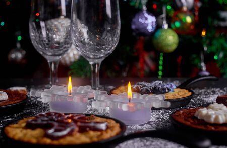 Burning candles on the dinning table with food, decorated Christmas tree. Christmas night.の写真素材