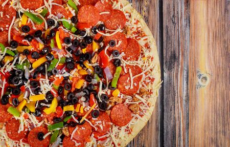 Tasty supreme pizza with black olives on wooden background.の写真素材