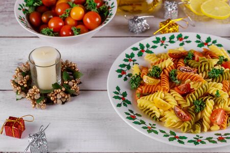 Christmas dinner. Tricolor rotini pasta with cherry tomato and candle. Holiday concept.の写真素材