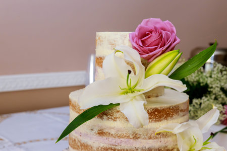 The top of a naked cake with rose and lily decoration. Wedding party cake.