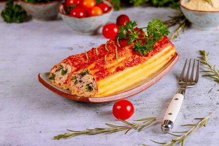Delicious pasta cannelloni stuffed with ricotta and spinach on plate with fork.の写真素材