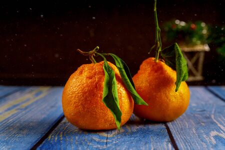Two tangerines with green leaf on wooden table.の写真素材