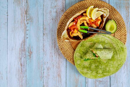 Spinach wrap with stir fry chicken and vegetable on wooden background.の写真素材