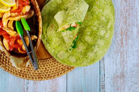 Spinach wrap with stir fry chicken and vegetable on wooden background.の写真素材