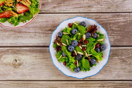 Spring green salad with blueberry, cranberry and slivered almond on woodwn table.の写真素材