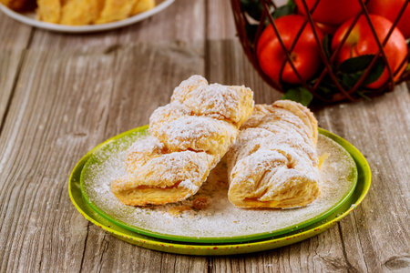 Powdered sugar sprinkle on apple strudel with fresh apples in wire basket.