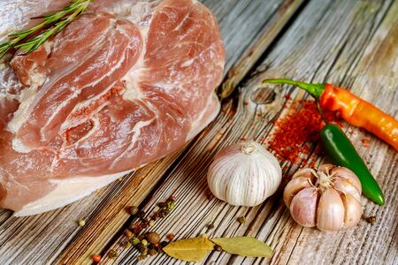 Prepare pork shoulder to cook with spices and garlic on wooden background.の写真素材
